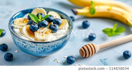 Blueberries, banana bites with greek yoghurt, granola and honey in bowl 114838034