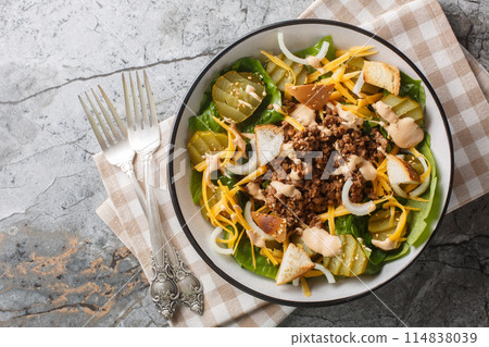 Cheeseburger, hamburger or burger keto salad with crunchy lettuce, creamy burger sauce, ground beef, pickles, cheese and onions closeup on the bowl. Horizontal top view Cheeseburger, hamburger or burger keto salad with crunchy lettuce, creamy burger sauce, ground beef, pickles, cheese and onions closeup on the bowl. Horizontal top view 114838039
