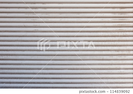 Closeup of a weathered metal shutter with horizontal folding lines 114839092