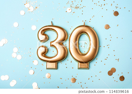 Gold candles in the form of number thirty on blue background with confetti. 30 years anniversary celebration. 114839616