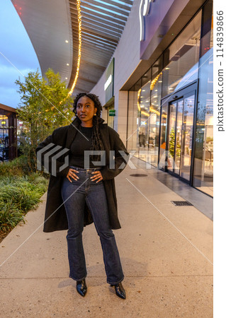 Confident woman posing in urban setting at night, showcasing independence and trendy fashion sense Confident woman posing in urban setting at night, showcasing independence and trendy fashion sense 114839866