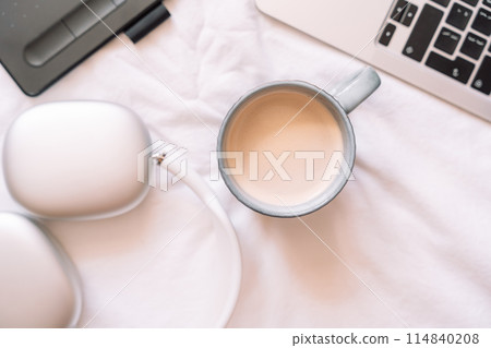 Cozy workplace with wireless headphones and laptop with a cup of coffee and graphics tablet Cozy workplace with wireless headphones and laptop with a cup of coffee and graphics tablet 114840208