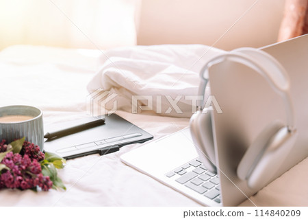 Cozy workplace with wireless headphones hanging on laptop 114840209