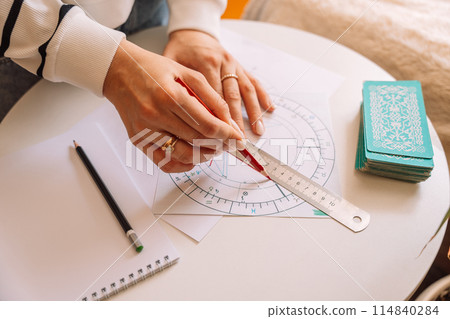 Woman drawing with pencil and ruler on natal chart Woman drawing with pencil and ruler on natal chart 114840284