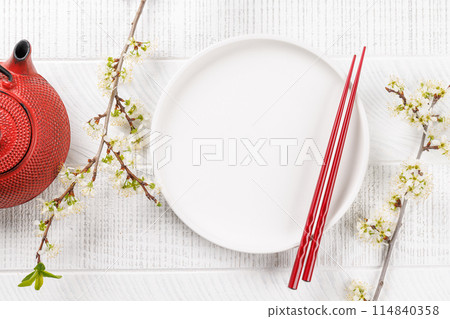Table adorned with cherry blossom branch and chopsticks, epitomizing Japanese food culture Table adorned with cherry blossom branch and chopsticks, epitomizing Japanese food culture 114840358