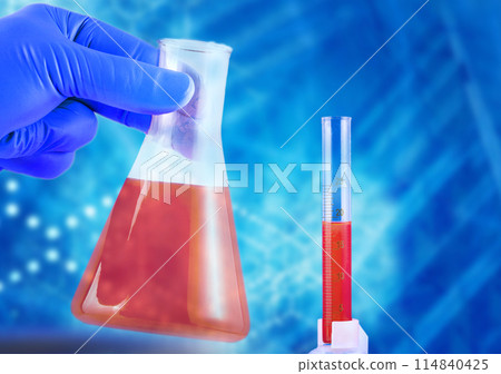 Laboratory flask in hands in blue gloves and a beaker with red liquid on a blue background 114840425
