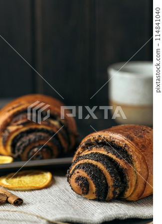 buns with poppy seeds and a cup of coffee on dark wood background 114841040