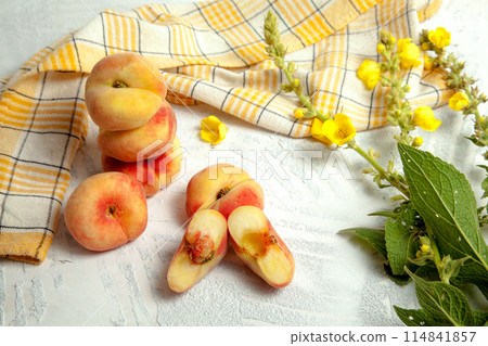 Halves and several whole saturn peaches or flat peach on white wooden background.. Halves and several whole saturn peaches or flat peach on white wooden background.. 114841857