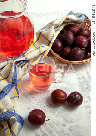 Plum Compote in jug with purple plums on white wooden background. . 114841871