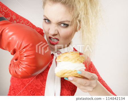 Woman fighting off bad food, boxing cream puff cake Woman fighting off bad food, boxing cream puff cake 114842134