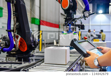 Manager check and control automation robot arms holding a white box and worker operating a robot machine with a control panel 114842679