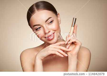 Portrait beautiful young woman with foundation bottle Portrait beautiful young woman with foundation bottle 114842879