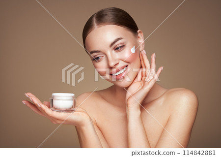 Beauty woman applying cream on her face Beauty woman applying cream on her face 114842881