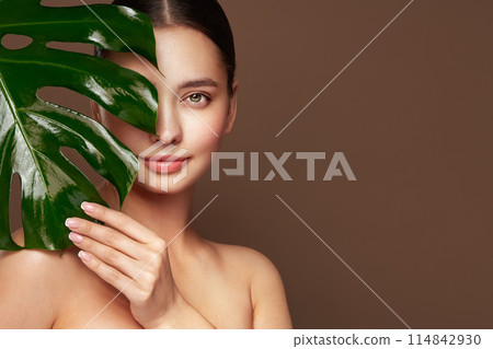Close up woman face with green exotic leaf 114842930