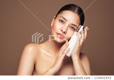 Smiling woman holds bottle with cosmetic milk 114842933
