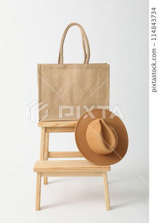 A bag with a hat on a wooden chair A bag with a hat on a wooden chair 114843734