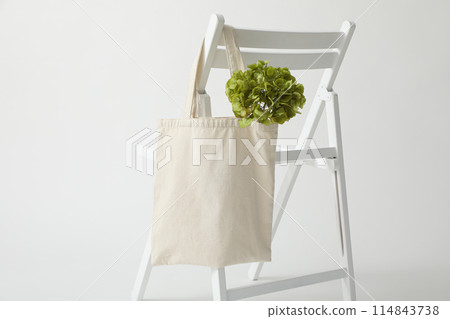 A white bag hangs on a white chair 114843738