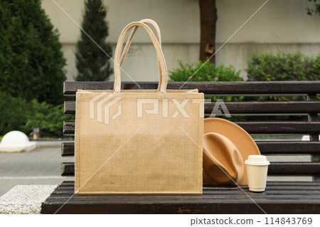 A bag with coffee and a hat on a bench A bag with coffee and a hat on a bench 114843769