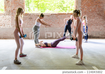 Group fitness class with a personal trainer in an industrial space for a motivating workout Group fitness class with a personal trainer in an industrial space for a motivating workout 114843802