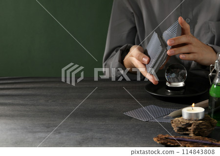 A tarologist makes a spread, on a dark background. 114843808