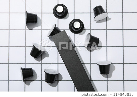 Black coffee capsules and box on light background, top view Black coffee capsules and box on light background, top view 114843833