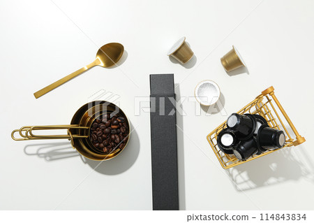 Coffee capsules on shopping tray and coffee beans in scoops, box and spoon on white background, top view Coffee capsules on shopping tray and coffee beans in scoops, box and spoon on white background, top view 114843834