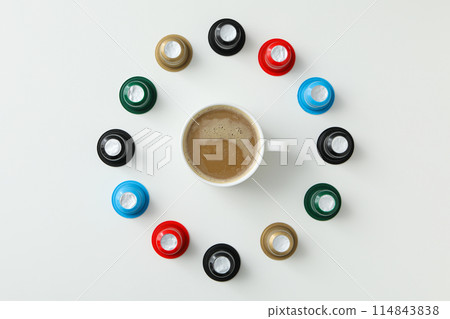 Colored coffee capsules and cup with coffee drink on white background, top view 114843838