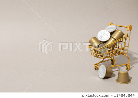 Golden coffee capsules in shopping tray on beige background, space for text 114843844