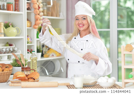 Portrait of beautiful young woman in chefs hat baking at home Portrait of beautiful young woman in chefs hat baking at home 114844041