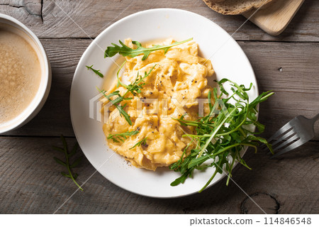 Scrambled eggs with arugula salad for breakfast. 114846548