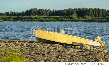 orange boat parked on a rocky shore, against a background of sky and forest orange boat parked on a rocky shore, against a background of sky and forest 114847602