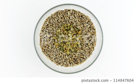 peeled sunflower seeds and pumpkin seeds in a plate on a white background, isolates peeled sunflower seeds and pumpkin seeds in a plate on a white background, isolates 114847604