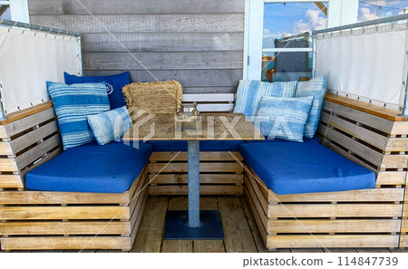 Create an appealing outdoor seating area with blue cushions and wooden pallets for a cozy vibe 114847739