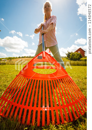 Unusual angle of woman raking leaves Unusual angle of woman raking leaves 114848572