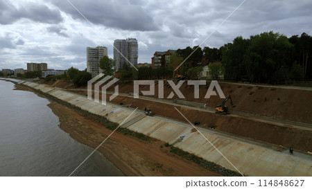 Construction and strengthening of a new safety embankment along the river. Clip. Aerial view ov the improving city area. 114848627