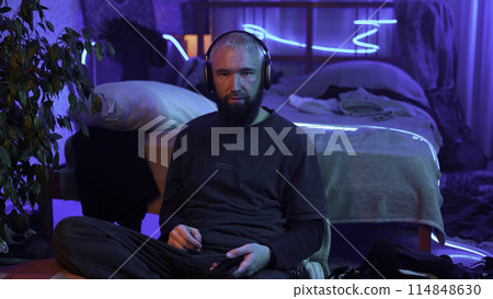 A guy in a neon room listening to music alone and relaxing. Media. Room of a teenager and mess. A guy in a neon room listening to music alone and relaxing. Media. Room of a teenager and mess. 114848630
