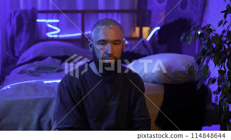 A guy in a neon room listening to music alone and relaxing. Media. Room of a teenager and mess. A guy in a neon room listening to music alone and relaxing. Media. Room of a teenager and mess. 114848644