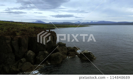 Bird eye view of calm ocean and stone rock cliffs at Oregon coast. Clip. Aerial of the ocean water surface and green meadows. Bird eye view of calm ocean and stone rock cliffs at Oregon coast. Clip. Aerial of the ocean water surface and green meadows. 114848689