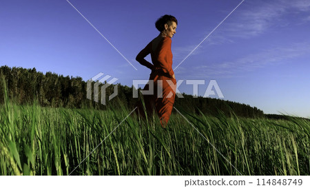 Portrait of an attractive woman in red dress in a field of fresh green wheat. Stock clip. Herbal background. amazing nature, farmland, growing cereals. Portrait of an attractive woman in red dress in a field of fresh green wheat. Stock clip. Herbal background. amazing nature, farmland, growing cereals. 114848749