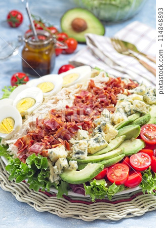 Cobb salad with greens, tomato, avocado, blue cheese, bacon, rotisserie chicken and eggs, vertical 114848893