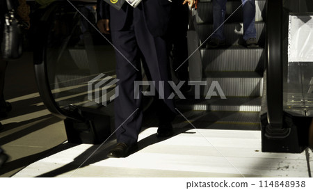 People using escalator at subway station. Media. Many men and women with bags moving down the escalator. 114848938