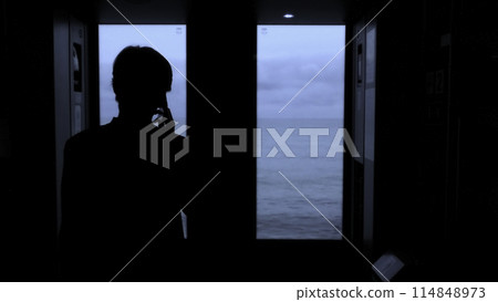 Young man standing next to a train window and looking outside Stock clip. Man with smartphone looking through the window on sea. 114848973