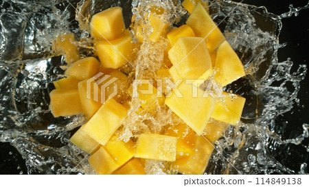 Fresh mango pieces falling into water, top down view 114849138
