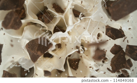 Tasty chocolate chunks falling into cream, top down view 114849168