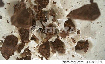 Tasty chocolate chunks falling into cream, top down view 114849171