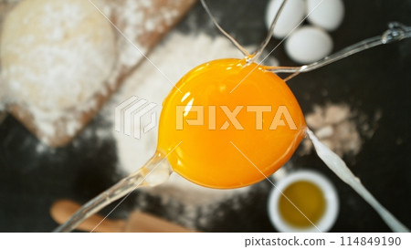 close up view of yolk falling on flour on black stone table close up view of yolk falling on flour on black stone table 114849190
