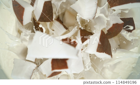 Fresh coconut pieces falling into cream, top down view Fresh coconut pieces falling into cream, top down view 114849196