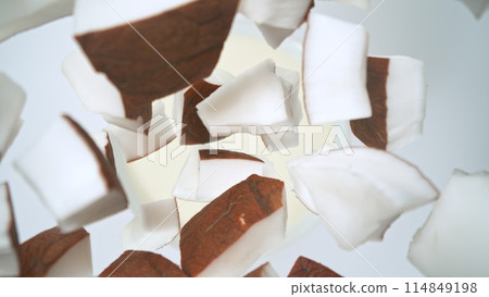 Fresh coconut pieces falling into cream, top down view 114849198