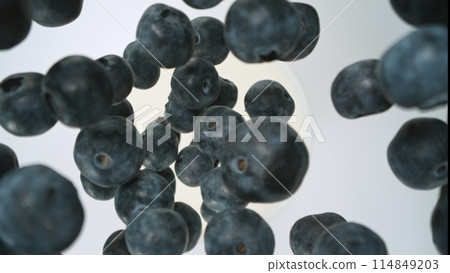 Fresh pieces of blueberries falling into milk, top down view, black background 114849203