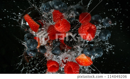Fresh pieces of berries falling into water, top down view, black background 114849206